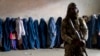 Боец "Талибана" стоит на страже, пока женщины ждут продовольственных пайков, раздаваемых группой гуманитарной помощи. Кабул, Афганистан. 23 мая 2023 г.
