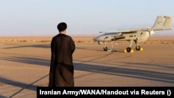 یک روحانی در جریان یک رزمایش نظامی در نقطه‌ای نامعلوم از ایران رو به یک پهپاد ایستاده است