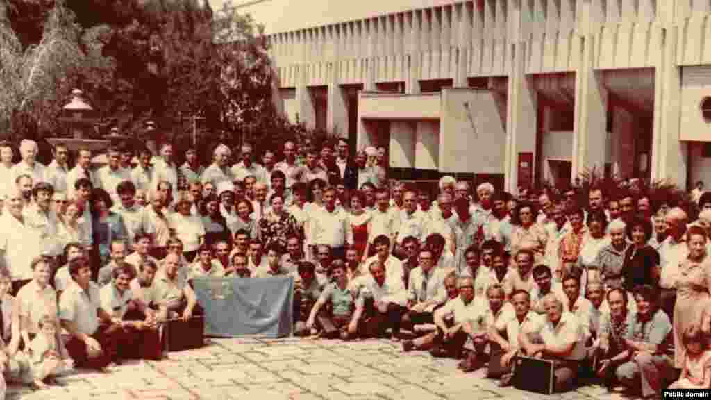 1991 senesi iyun ayı. Ekinci Qurultaynıñ iştirakçileri Aqmescitte. Eki Qurultay arasında 70 yıl keçti. 20-nci asırnıñ başında qabul etilgen milliy bayraq sürgünlikten qaytqan qırımtatarlarnıñ qollarında