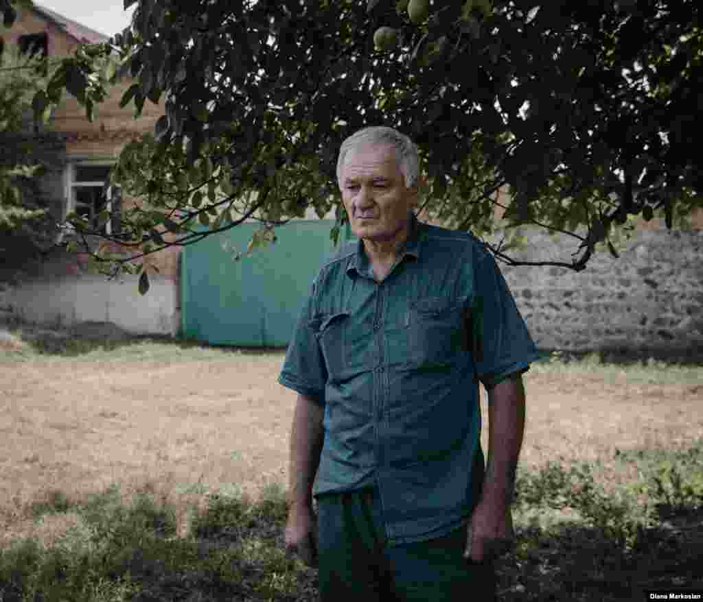 &laquo;Мені здається, що вона як і раніше з нами&raquo;, &ndash; говорить 63-річний Руслан Коков. Коли Оксана пішла в школу, щоб більше вже не повернутися ніколи, Руслан був на базарі. В її день народження Руслан і його 27-річний син Урузмага завжди сервірують для неї місце за столом. Вони їдять її улюблену їжу &ndash; кавуни, хурму, апельсини-корольки. На цій фотографії Руслан зображений на тлі свого будинку на вулиці Комінтерну. Школу №1 видно з вікна його кімнати. Під час облоги тут розташовувалися підрозділи російського спецназу. У заключній перестрілці було розбито скло на двох вікнах його будинку. За минулі десять років він так і не зібрався з духом їх полагодити. &laquo;Коли щось нагадує мені про цю трагедію, я тільки страшно засмучуюсь&raquo;, &ndash; говорить він.&nbsp; 