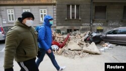 Люди проходят мимо поврежденных землетрясением автомобилей. Загреб, Хорватия, 22 марта 2020 года.