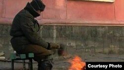 Житель города греется на улице у костра возле дома в Приозерске. Январь 2011 года. 