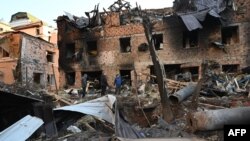Місцеві жителі оглядають пошкодження біля житлового будинку після нічної атаки російських безпілотників у Харкові, 31 грудня 2023 року