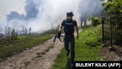 На передньому плані журналіст AFP, а позаду піднімається дим після обстрілу. Донеччина, 31 липня 2022 року