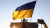 Украинадагы согушка каршы Берлинде өткөн акцияда тартылган сүрөт. Акциянын катышуучусу украин желегин көтөрүп турат. Сүрөт иллюстрация үчүн колдонулду