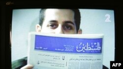 تصویری از ویدئویی که شالیط را در حال در دست گرفتن روزنامه فلسطین نشان می‌دهد